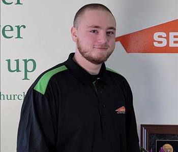 Crew chief standing in our office in front of our SERVPRO logo